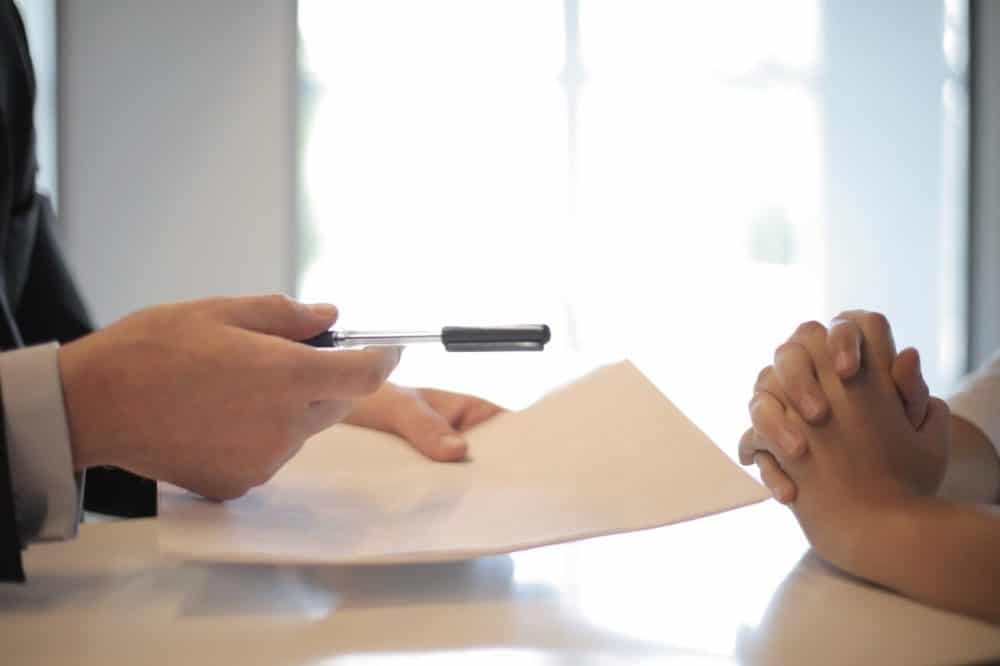 Insurance broker handing contract and pen to client