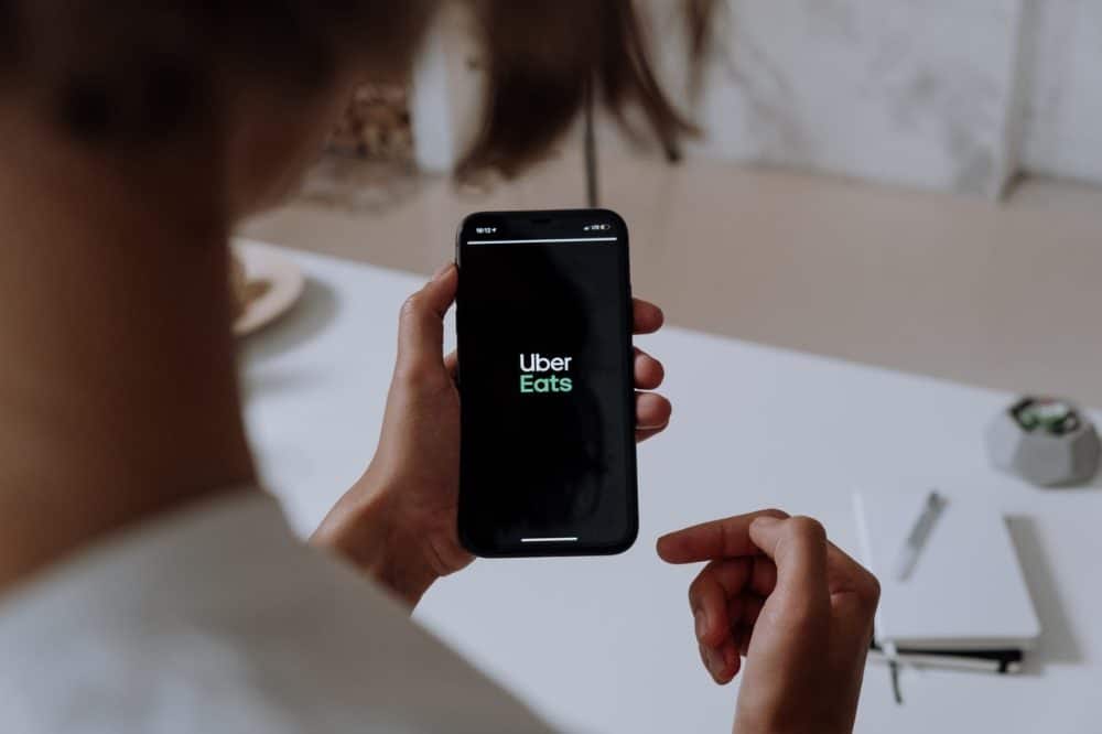 Person holding phone with Uber Eats logo on it