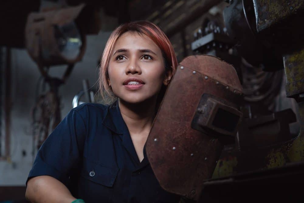 Female welder holding mask