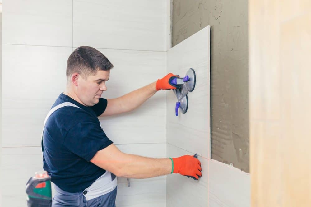 Male licensed tiler tiling wall